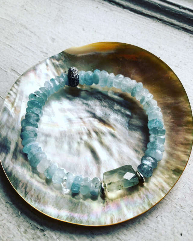 Blue glass bracelet displayed on a shell